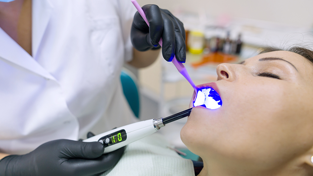 Dentist performing laser dentistry on patient using diode laser for soft tissue treatment