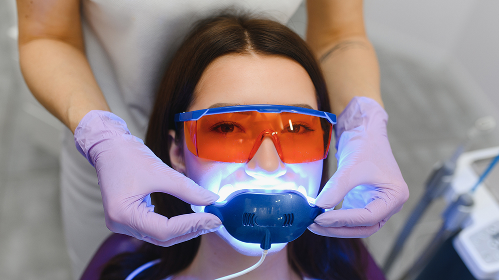 Dentist adjusting dental laser device and eyewear on patient before procedure