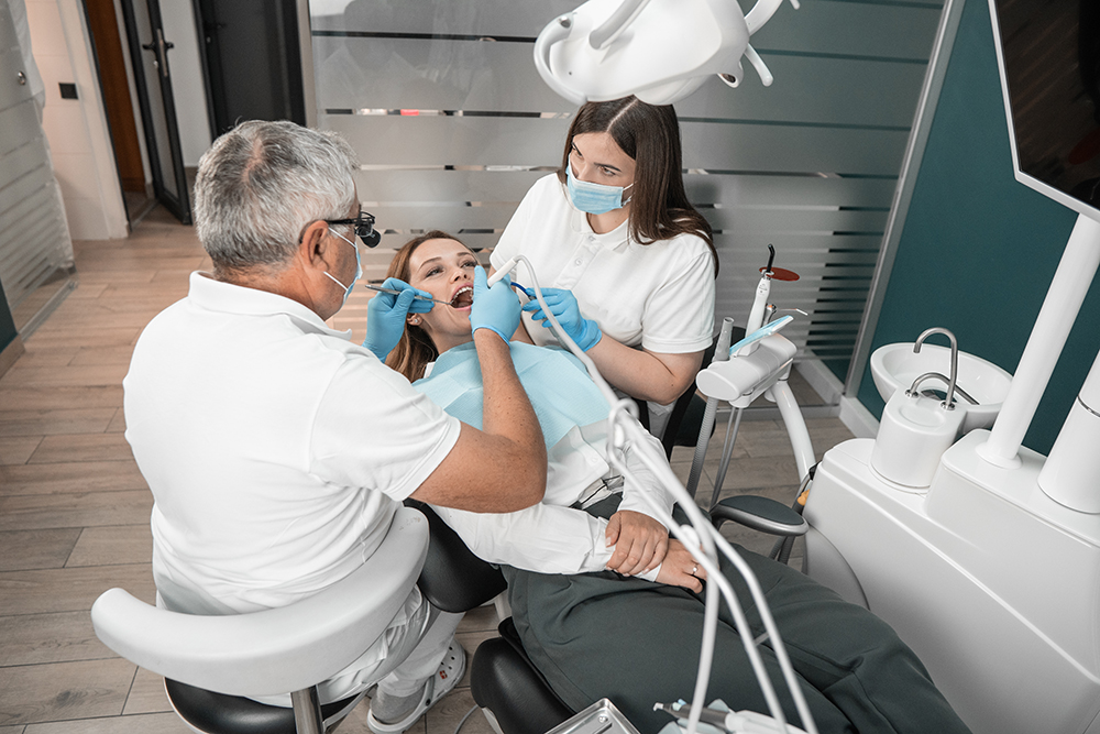 Female patient undergoing dental check-up with two professionals
