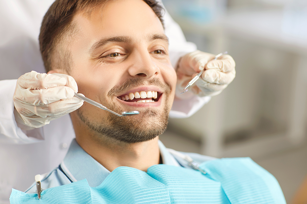 Man smiling during a dental crown procedure at the dentist’s office