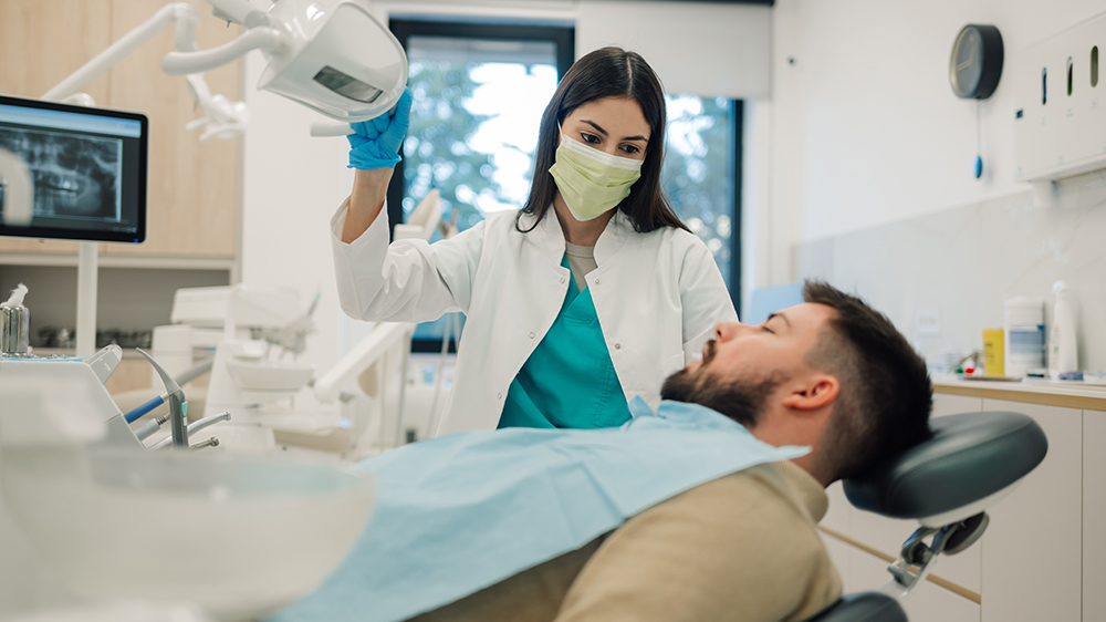 Dentist examining a male patient before starting Hollywood Smile treatment in a modern dental clinic