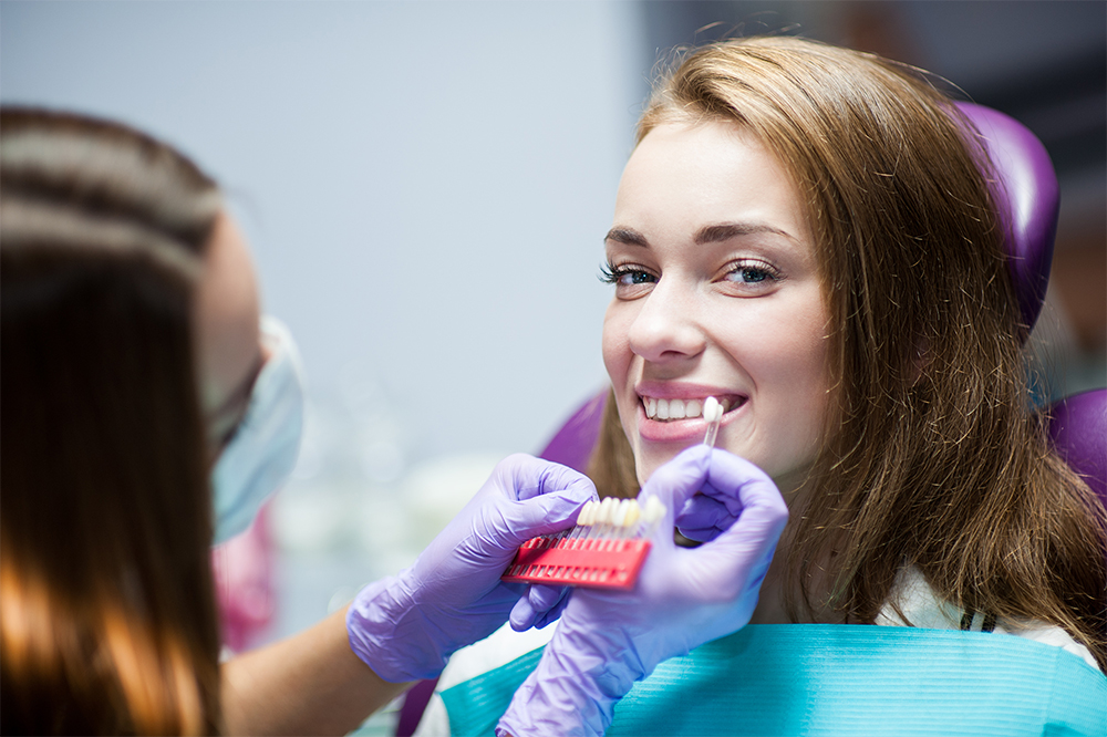Young woman getting her teeth examined before dental crown fitting